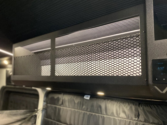 Overhead storage cabinet with a black powder coat finish and a mesh front design, mounted inside a van.