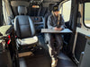 A person seated in a Sprinter van cabin, using a mobile device, with a空 table mounted on the side of the van interior