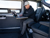 A person seated in a Sprinter van with a laptop on their lap, showcasing the interior and potential use of the VANNON Lagun B-Pillar Mount.