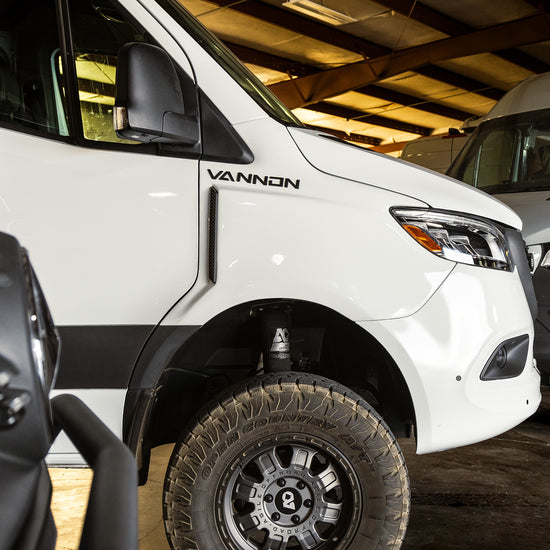 White van with VANNON FAF Fenders installed on the vehicle, displayed in a service setting with other vans in the background.