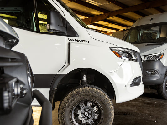 White van with VANNON FAF Fenders installed on the vehicle, displayed in a service setting with other vans in the background.