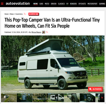 White pop-top camper van on a road with trees in the background, displayed on autoevolution website.