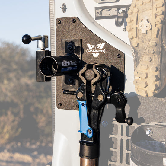 A Sprinter van rear door bike mount workstation attached to the vehicle's door, featuring aircraft grade aluminum supports and a textured powder-coat finish.