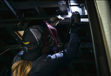 Person working on a vehicle's interior with tools in a dimly lit setting