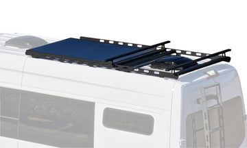 A black aluminum roof rack mounted on the roof of a white Sprinter van.